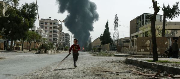A child runs along a street in front of clouds of smoke billowing following a reported air strike on Douma, the main town of Syria's rebel enclave of Eastern Ghouta - Sputnik International