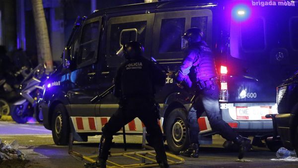 Catalan Mossos d'Esquadra regional police officers run by a police van after metal raining were thrown during a protest after the detention of deposed leader of Catalonia's pro-independence party Carles Puigdemont in Barcelona, Spain, Sunday, March 25, 2018. Puigdemont was arrested Sunday by German police on an international warrant as he tried to enter the country from Denmark. - Sputnik International