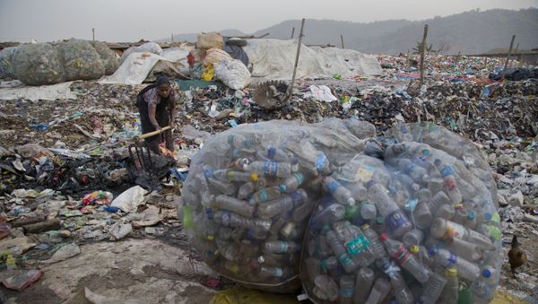 An Indian woman makes a drain for dirty water to pass next to plastic bottles collected for recycling at a garbage dumping site in Gauhati, India, Wednesday, Mar 7, 2018 - Sputnik International