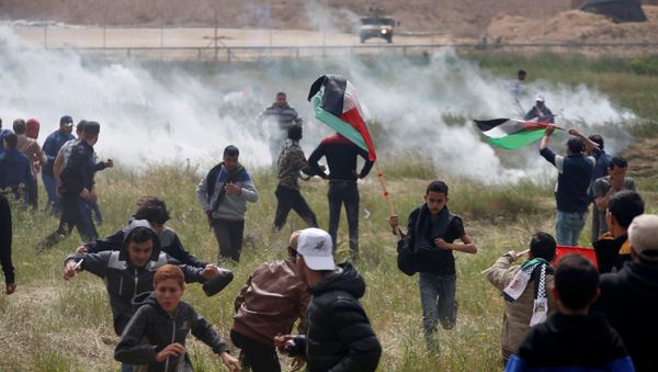Palestinians run from tear gas fired by Israeli troops during clashes, during a tent city protest along the Israel border with Gaza, demanding the right to return to their homeland, east of Gaza Palestinians run from tear gas fired by Israeli troops during clashes, during a tent city protest along the Israel border with Gaza, demanding the right to return to their homeland, east of Gaza - Sputnik International