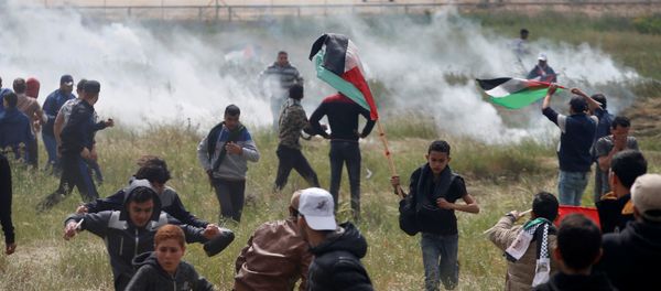 Palestinians run from tear gas fired by Israeli troops during clashes, during a tent city protest along the Israel border with Gaza, demanding the right to return to their homeland, east of Gaza Palestinians run from tear gas fired by Israeli troops during clashes, during a tent city protest along the Israel border with Gaza, demanding the right to return to their homeland, east of Gaza - Sputnik International