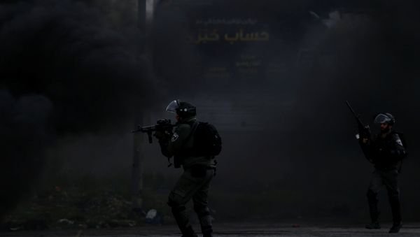 An Israeli border policeman points his weapon at Palestinian demonstrators during clashes at a protest marking Land Day, near Ramallah, in the occupied West Bank March 30, 2018. - Sputnik International