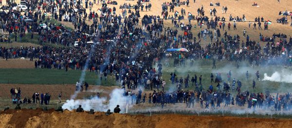 Israeli soldiers shoot tear gas from the Israeli side of the Israel-Gaza border, as Palestinians protest on the Gaza side of the border, March 30, 2018 - Sputnik International