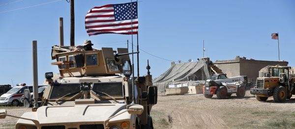 A U.S. soldier, left, sits on an armored vehicle behind a sand barrier at a newly installed position near the tense front line between the U.S-backed Syrian Manbij Military Council and the Turkish-backed fighters, in Manbij, north Syria, Wednesday, April 4, 2018 - Sputnik International