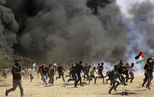 Palestinian protesters run to cover from teargas fired by Israeli soldiers during clashes with Israeli troops along Gaza's border with Israel, east of Khan Younis, Gaza Strip, Friday, April 6, 2018 - Sputnik International