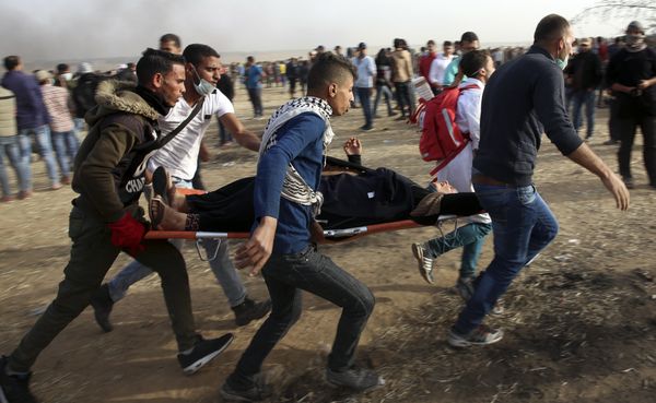 Palestinian protesters evacuate a wounded woman during clashes with Israeli troops along Gaza's border with Israel, Friday, April 13, 2018.  - Sputnik International