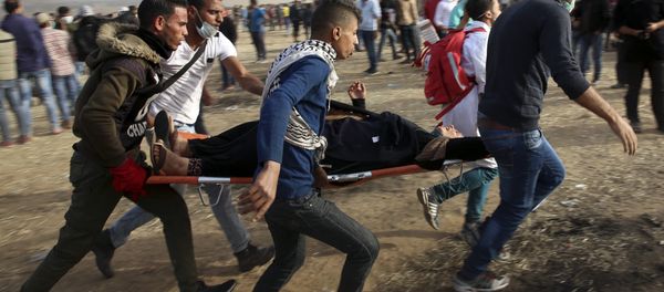 Palestinian protesters evacuate a wounded woman during clashes with Israeli troops along Gaza's border with Israel, Friday, April 13, 2018. Palestinian protesters evacuate a wounded woman during clashes with Israeli troops along Gaza's border with Israel, Friday, April 13, 2018. - Sputnik International