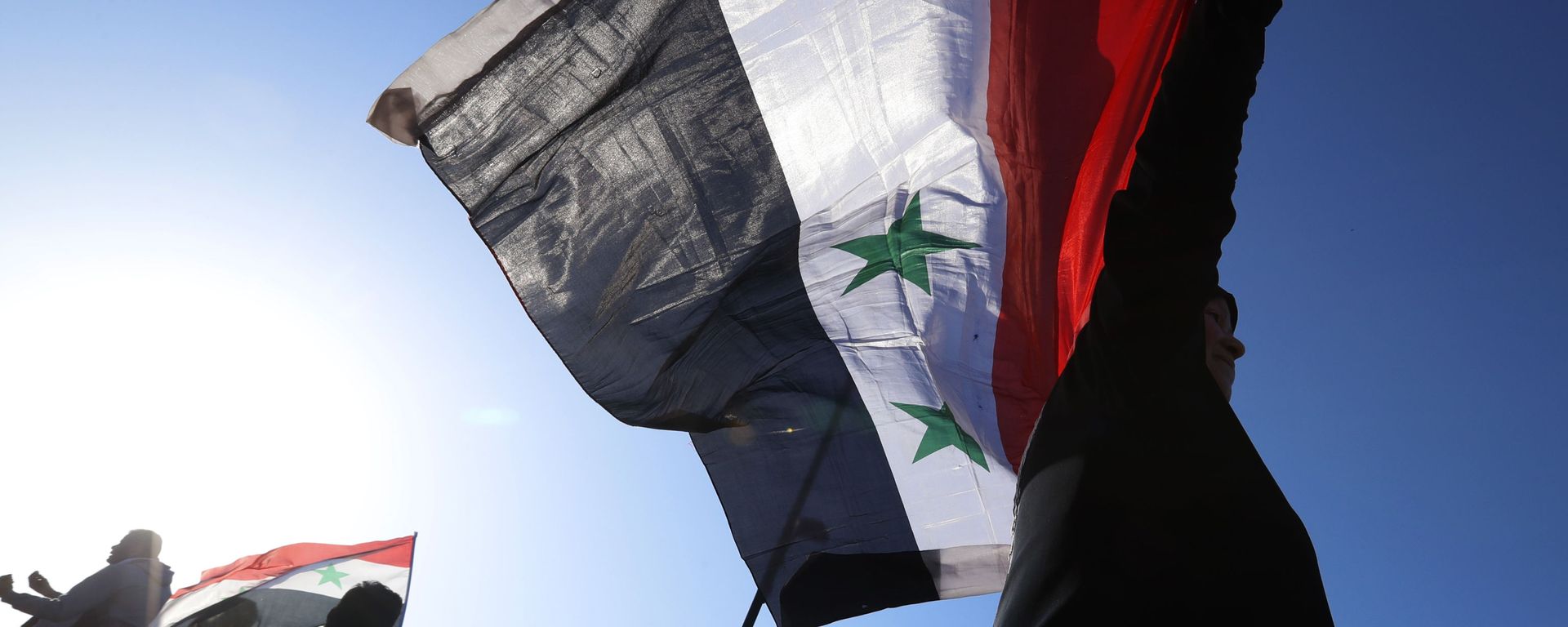 A Syrian government supporter holds up a Syrian national flag as he chants slogans against U.S. President Trump during demonstrations following a wave of U.S., British and French military strikes to punish President Bashar Assad for suspected chemical attack against civilians, in Damascus, Syria, Saturday, April 14, 2018 A Syrian government supporter holds up a Syrian national flag as he chants slogans against U.S. President Trump during demonstrations following a wave of U.S., British and French military strikes to punish President Bashar Assad for suspected chemical attack against civilians, in Damascus, Syria, Saturday, April 14, 2018 - Sputnik International, 1920, 23.09.2021