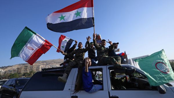 Syrian government supporters wave Syrian, Iranian and Russian flags as they chant slogans against U.S. President Trump during demonstrations following a wave of U.S., British and French military strikes to punish President Bashar Assad for suspected chemical attack against civilians, in Damascus, Syria, Saturday, April 14, 2018 - Sputnik International