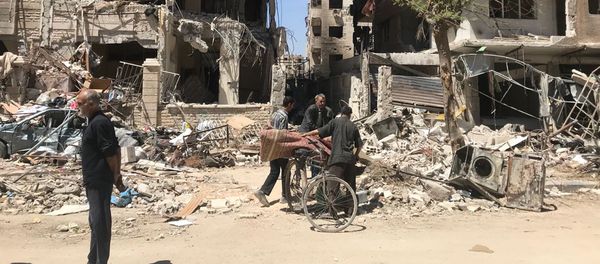 People stand in front of damaged buildings, in the town of Douma, the site of a suspected chemical weapons attack, near Damascus, Syria, Monday, April 16, 2018 People stand in front of damaged buildings, in the town of Douma, the site of a suspected chemical weapons attack, near Damascus, Syria, Monday, April 16, 2018 - Sputnik International