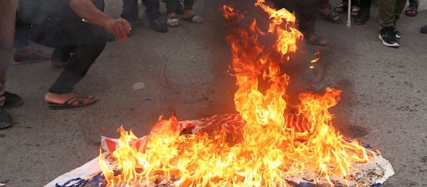 Protesters burn representations of US flags during a protest against the US-led missile attack on Syria, in Tahrir Square, Baghdad, Iraq, Sunday, April 15, 2018. - Sputnik International