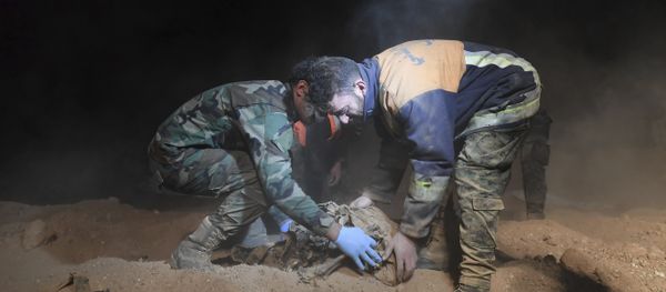 Syrian security forces members remove human remains at the site were discovered two mass graves believed to contain the bodies of civilians and troops killed by Daesh, in the village of Wawi near the northern city of Raqqa, Syria (File) - Sputnik International