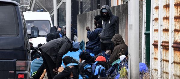 Migrants gather by the ringroad leading to the harbour on March 30, 2018 in Calais, near a police van patrolling (Rear L) - Sputnik International