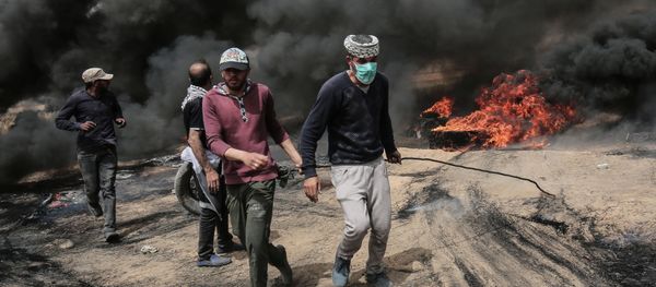 Palestinian protesters pull on a burning tire during clashes with Israeli forces on April 20, 2018, east of Khan Yunis, in the southern Gaza Strip during mass protests along the border of the Palestinian enclave, dubbed The Great March of Return, which has the backing of Gaza's Islamist rulers Hamas Palestinian protesters pull on a burning tire during clashes with Israeli forces on April 20, 2018, east of Khan Yunis, in the southern Gaza Strip during mass protests along the border of the Palestinian enclave, dubbed The Great March of Return, which has the backing of Gaza's Islamist rulers Hamas - Sputnik International