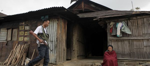 An armed cadre of the National Socialist Council of Nagaland (NSCN-IM), left, walks past an elderly woman sitting outside a traditional Naga hut, during a visit by the NSCN-IM General-Secretary Thuingaleng Muivah, at Viswema village, about 25 kilometers (16 miles) south of Kohima, capital of the northeastern Indian state of Nagaland (File) - Sputnik International