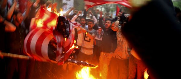 Iranian demonstrators burn representations of the U.S. flag during a protest in front of the former U.S. Embassy in response to President Donald Trump's decision Tuesday to pull out of the nuclear deal and renew sanctions, in Tehran, Iran, Wednesday, May 9, 2018 - Sputnik International