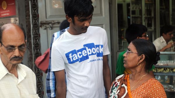 An Indian mother (R) interacts with her son wearing a t-shirt with a Facebook logo at a roadside vegetable market as an officegoer walks past in Mumbai (File) - Sputnik International