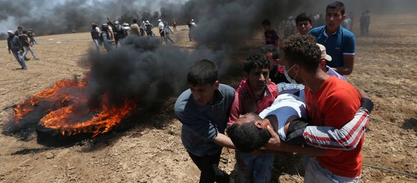 A wounded Palestinian demonstrator is evacuated during a protest against U.S. embassy move to Jerusalem and ahead of the 70th anniversary of Nakba, at the Israel-Gaza border in the southern Gaza Strip May 14, 2018 - Sputnik International