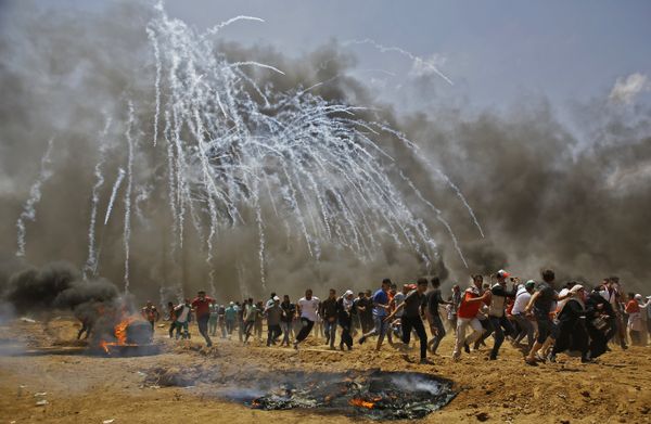 Palestinians run for cover from tear gas during clashes with Israeli security forces near the border between Israel and the Gaza Strip, east of Jabalia on May 14, 2018 - Sputnik International