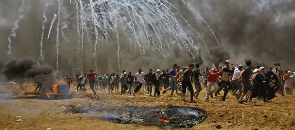 Palestinians run for cover from tear gas during clashes with Israeli security forces near the border between Israel and the Gaza Strip, east of Jabalia on May 14, 2018 - Sputnik International