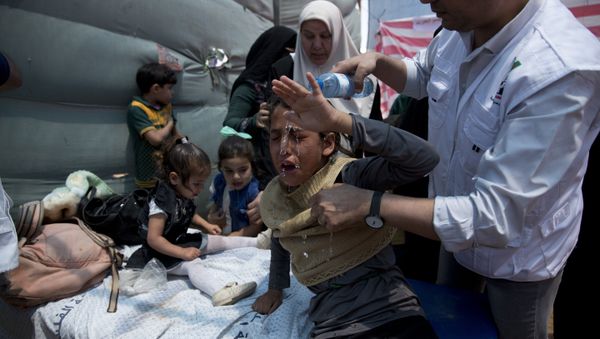 Medics treat Palestinian children suffering from teargas inhalation during a protest near Beit Lahiya, Gaza Strip, Monday, May 14, 2018 - Sputnik International