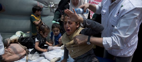 Medics treat Palestinian children suffering from teargas inhalation during a protest near Beit Lahiya, Gaza Strip, Monday, May 14, 2018 - Sputnik International
