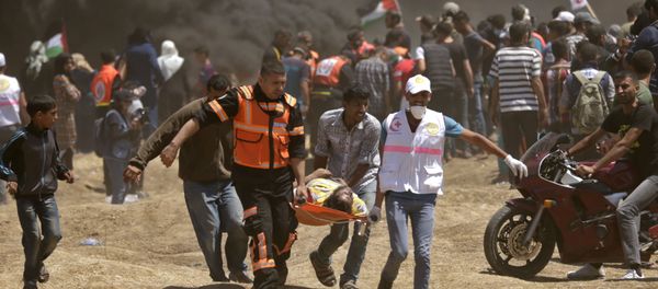 Palestinians carry a demonstrator injured during clashes with Israeli forces near the border between the Gaza strip and Israel east of Gaza City on May 14, 2018, as Palestinians readied for protests over the inauguration of the US embassy following its controversial move to Jerusalem Palestinians carry a demonstrator injured during clashes with Israeli forces near the border between the Gaza strip and Israel east of Gaza City on May 14, 2018, as Palestinians readied for protests over the inauguration of the US embassy following its controversial move to Jerusalem - Sputnik International