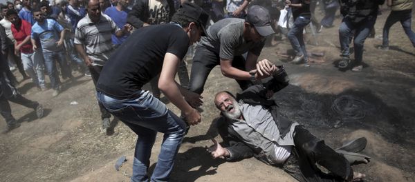 An elderly Palestinian man falls on the ground after being shot by Israeli troops during a deadly protest at the Gaza Strip's border with Israel, east of Khan Younis, Gaza Strip, Monday, May 14, 2018 An elderly Palestinian man falls on the ground after being shot by Israeli troops during a deadly protest at the Gaza Strip's border with Israel, east of Khan Younis, Gaza Strip, Monday, May 14, 2018 - Sputnik International