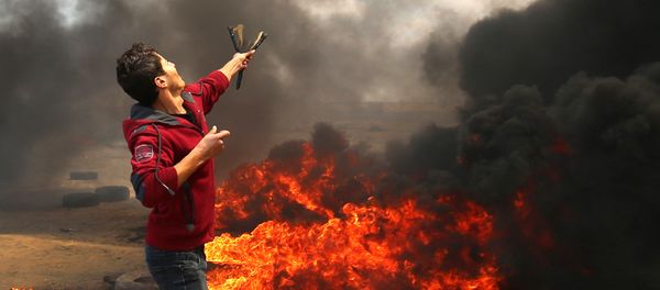 A Palestinian man uses a slingshot during clashes with Israeli forces along the border with the Gaza strip east of Khan Yunis on May 14, 2018, as Palestinians protest over the inauguration of the US embassy following its controversial move to Jerusalem - Sputnik International