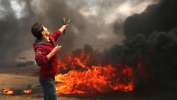 A Palestinian man uses a slingshot during clashes with Israeli forces along the border with the Gaza strip east of Khan Yunis on May 14, 2018, as Palestinians protest over the inauguration of the US embassy following its controversial move to Jerusalem - Sputnik International