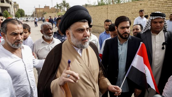 Iraqi Shiite cleric and leader Moqtada al-Sadr (C-L) shows his ink-stained index finger and holds a national flag while surrounded by people outside a polling station in the central holy city of Najaf on May 12, 2018 as the country votes in the first parliamentary election since declaring victory over the Islamic State (IS) group - Sputnik International