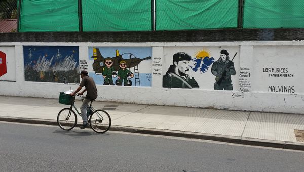 A man cycles past a mural about the Malvinas War on the wall of a military base in Buenos Aires - Sputnik International