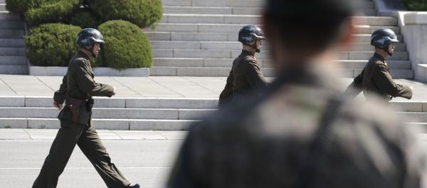 In this April 18, 2018 photo, North Korean soldiers march as a South Korean soldier, center, stands guard during a press tour at the border village of Panmunjom in the Demilitarized Zone, South Korea In this April 18, 2018 photo, North Korean soldiers march as a South Korean soldier, center, stands guard during a press tour at the border village of Panmunjom in the Demilitarized Zone, South Korea - Sputnik International