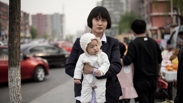 A mother holds her baby as she walks in a market in Shunyi on the outskirts of Beijing on April 13, 2017 A mother holds her baby as she walks in a market in Shunyi on the outskirts of Beijing on April 13, 2017 - Sputnik International