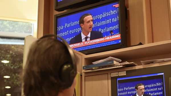 A journalist watches the speech of Facebook CEO Mark Zuckerberg on a television screen, in the press room, during his audition on the data privacy scandal on May 22, 2018 at the European Union headquarters in Brussels A journalist watches the speech of Facebook CEO Mark Zuckerberg on a television screen, in the press room, during his audition on the data privacy scandal on May 22, 2018 at the European Union headquarters in Brussels - Sputnik International