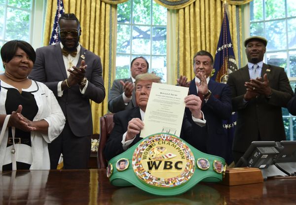 President Trump holds up the pardon as Deontay Wilder (left) and Lennox Lewis (right) applaud - Sputnik International