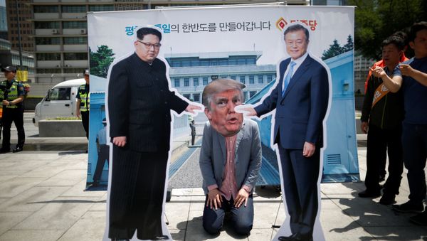 A man wearing a mask of U.S. President Donald Trump kneels down between cutouts of North Korean leader Kim Jong Un and South Korean President Moon Jae-in during an anti-U.S. President Donald Trump rally near U.S. embassy in Seoul, South Korea, May 25, 2018 - Sputnik International