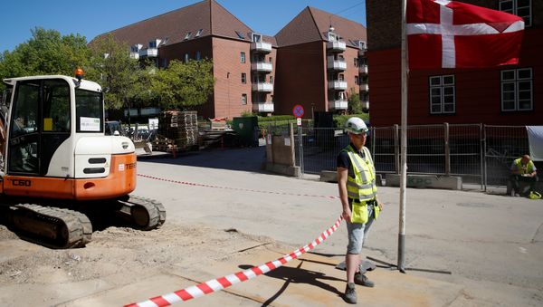 A worker stands beside a Danish flag on a construction site of new housing being built next to Mjolnerparken, a housing estate that features on the Danish government's Ghetto List, in Copenhagen, Denmark, May 8, 2018 A worker stands beside a Danish flag on a construction site of new housing being built next to Mjolnerparken, a housing estate that features on the Danish government's Ghetto List, in Copenhagen, Denmark, May 8, 2018 - Sputnik International