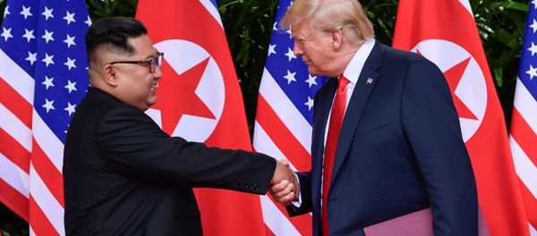 U.S. President Donald Trump and North Korea's leader Kim Jong Un shake hands during the signing of a document after their summit at the Capella Hotel on Sentosa island in Singapore June 12, 2018 - Sputnik International