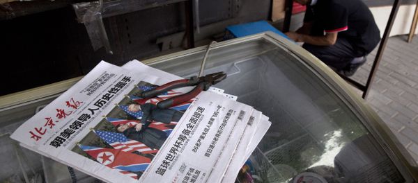 A worker makes repairs at a newspaper stand with front page photos of the meeting in Singapore between U.S. President Donald Trump and North Korean leader Kim Jong Un in Beijing, China, Tuesday, June 12, 2018 - Sputnik International