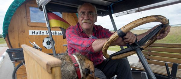 Soccer fan from Pforzheim, Germany, Hubert Wirth, 70, with his dog Hexe, drives his tractor with a trailer to attend the FIFA 2018 World Cup in Russia near the village of Yasen, Belarus June 7, 2018 - Sputnik International