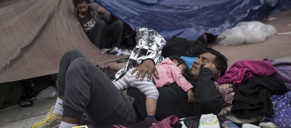 A migrant father and child rest outside the El Chaparral port of entry building at the US-Mexico border in Tijuana, Mexico - Sputnik International