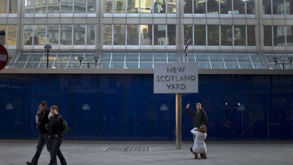 A tourist poses for a photograph by the rotating sign outside New Scotland Yard, the headquarters building of London's Metropolitan Police force in central London - Sputnik International