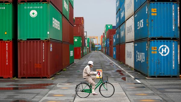 A worker rides a bicycle in a container area at a port in Tokyo (File) A worker rides a bicycle in a container area at a port in Tokyo (File) - Sputnik International