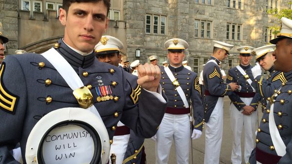 In this May 2016 photo provided by Spenser Rapone, Rapone raises his left fist while displaying a sign inside his hat that reads Communism will win, after graduating from the United States Military Academy at West Point, N.Y. - Sputnik International