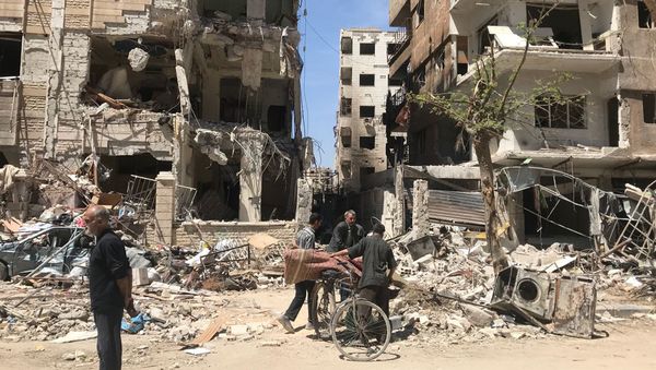 People stand in front of damaged buildings, in the town of Douma, the site of a suspected chemical weapons attack, near Damascus, Syria, Monday, April 16, 2018 - Sputnik International