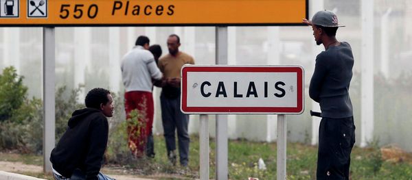 Migrants stand near a city sign along a road near the makeshift camp called The New Jungle in Calais - Sputnik International