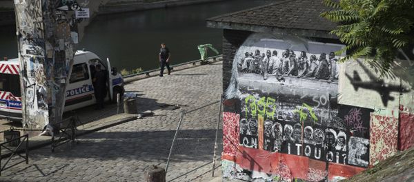 French police officer patrol past a mural depicting migrants (L) and an aeroplane (R) with the words underneath that read, 'What do we do?' painted and plastered on a structure along the banks of Canal Saint Martin where a former migrants camp was evacuated by the French authorities, on June 13, 2018 French police officer patrol past a mural depicting migrants (L) and an aeroplane (R) with the words underneath that read, 'What do we do?' painted and plastered on a structure along the banks of Canal Saint Martin where a former migrants camp was evacuated by the French authorities, on June 13, 2018 - Sputnik International