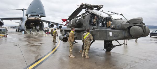 An AH-64 Apache attack helicopter stands in front of a Galaxy C-5 transport plane at the US Air Base in Ramstein, western Germany, on February 22, 2017. - Sputnik International