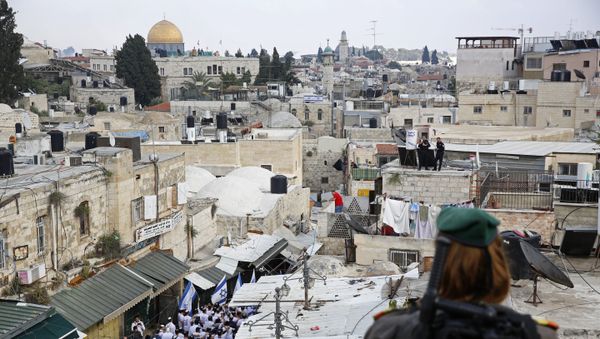 An Israeli border police officer watches as Israelis wave national flags inside the Old City's Damascus Gate in Jerusalem, Sunday, May 13, 2018 - Sputnik International